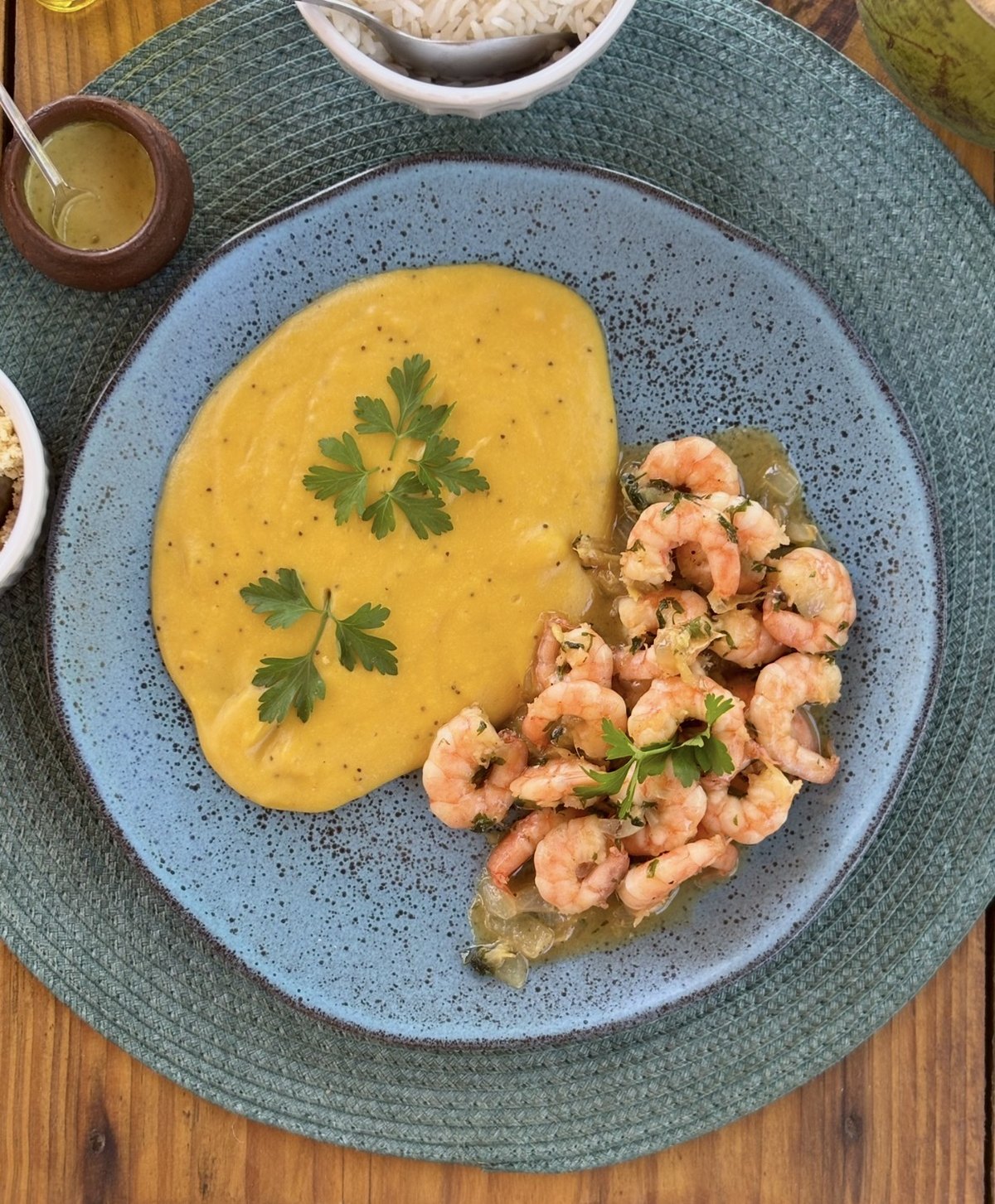 The plate from above: shrimp in sauce and plantain purée, with rice and farofa alongside.