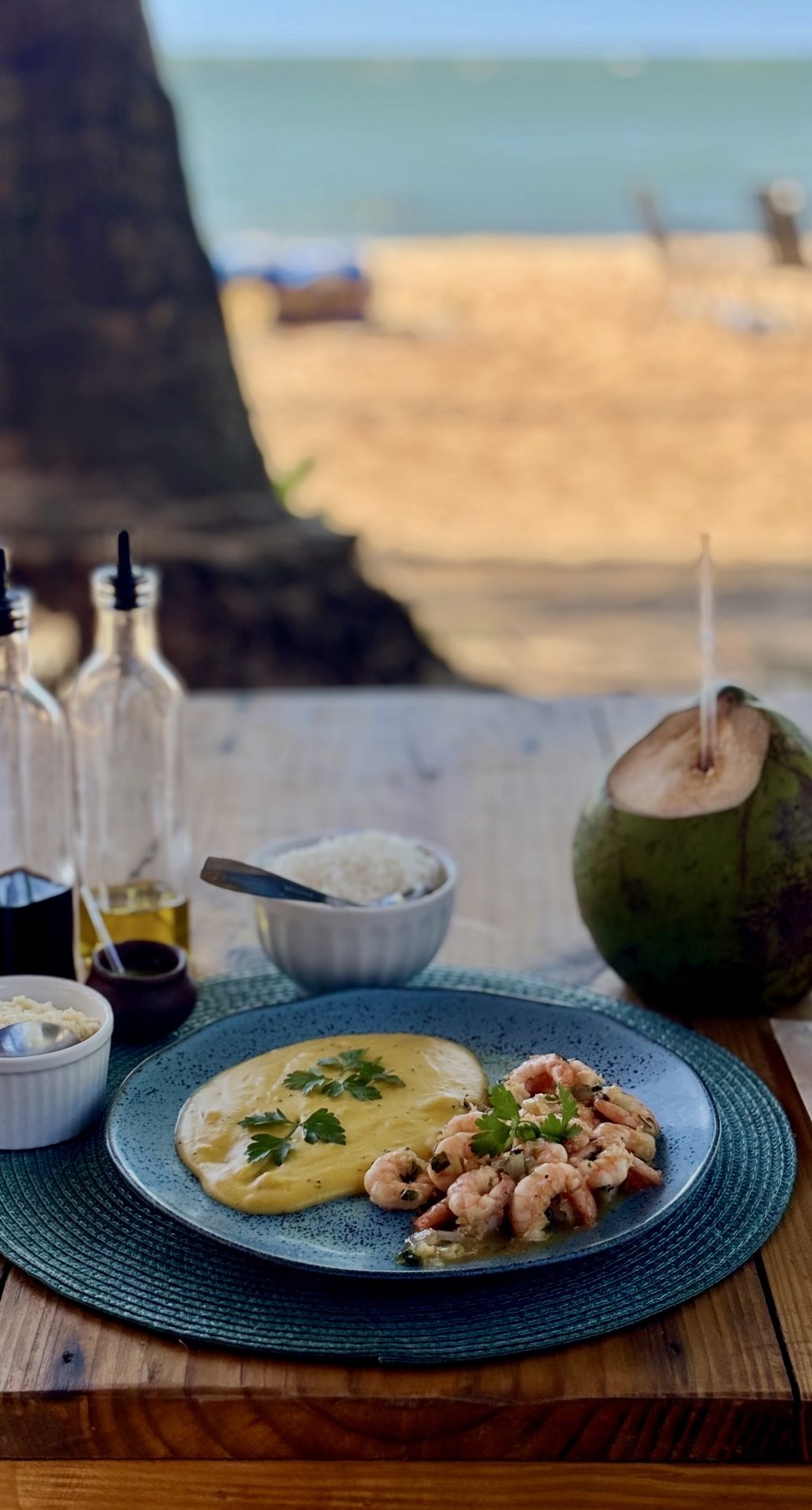 The plate on the beach hut table, with a coconut, the sand and the sea behind.
