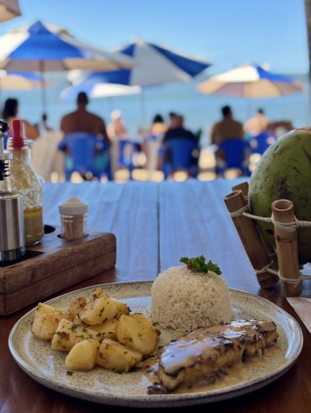 The plate on the beach hut table, with the umbrellas and the sea of Praia da Concha behind.