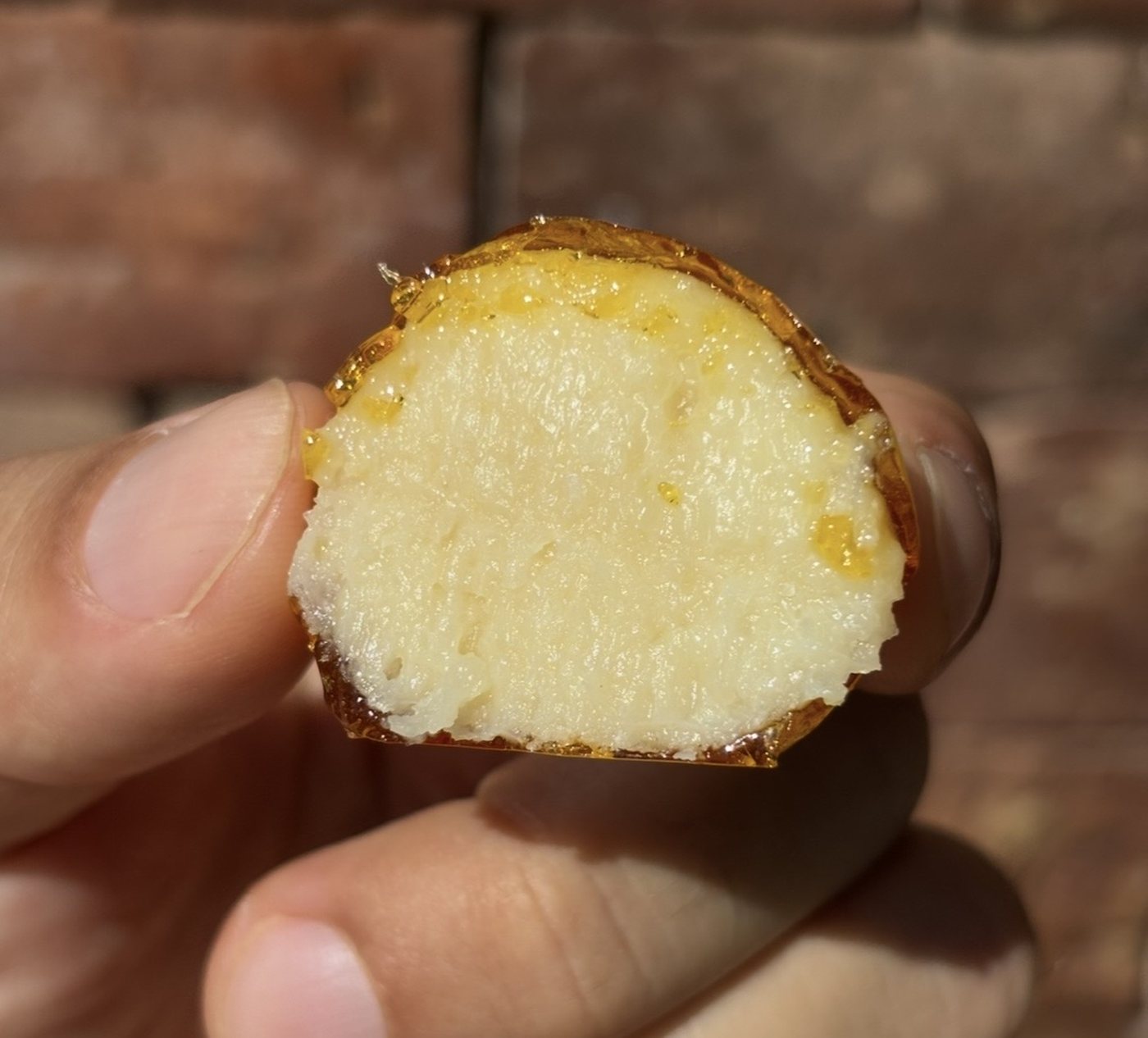 A bala baiana cut in half, the creamy coconut inside its caramel shell.