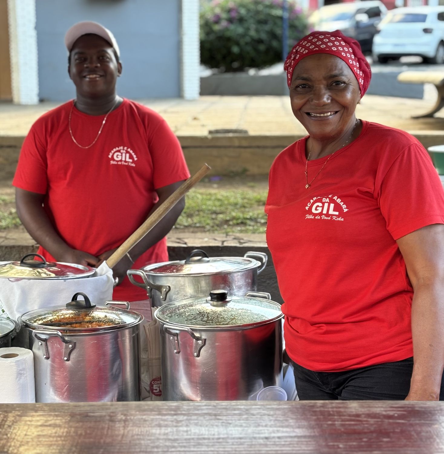 Gil and her son Silvio, both in red shirts, behind the acarajé counter at Praça do Fórum.