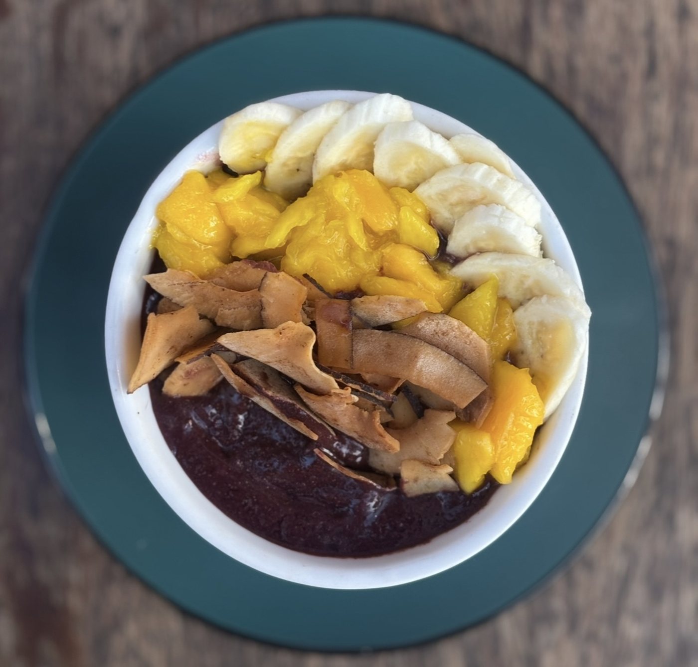 An açaí bowl from above, with banana, mango and coconut chips.