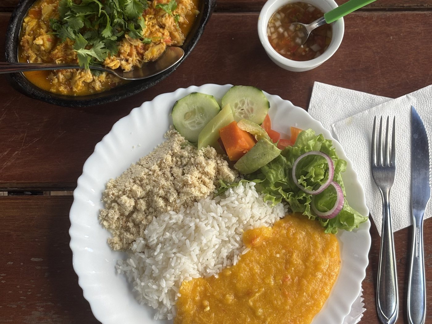 MM set plate with rice, pirão and salad, next to the pan of picked crab.