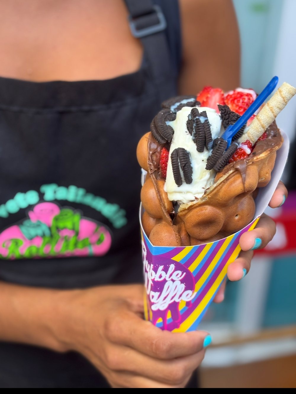 A bubble waffle with ice cream, strawberry, chocolate and wafer.