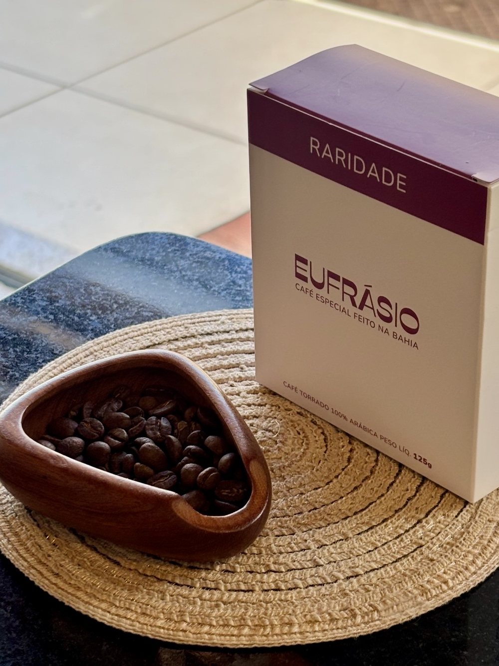 Beans in a wooden bowl, next to the box of specialty coffee from Bahia.
