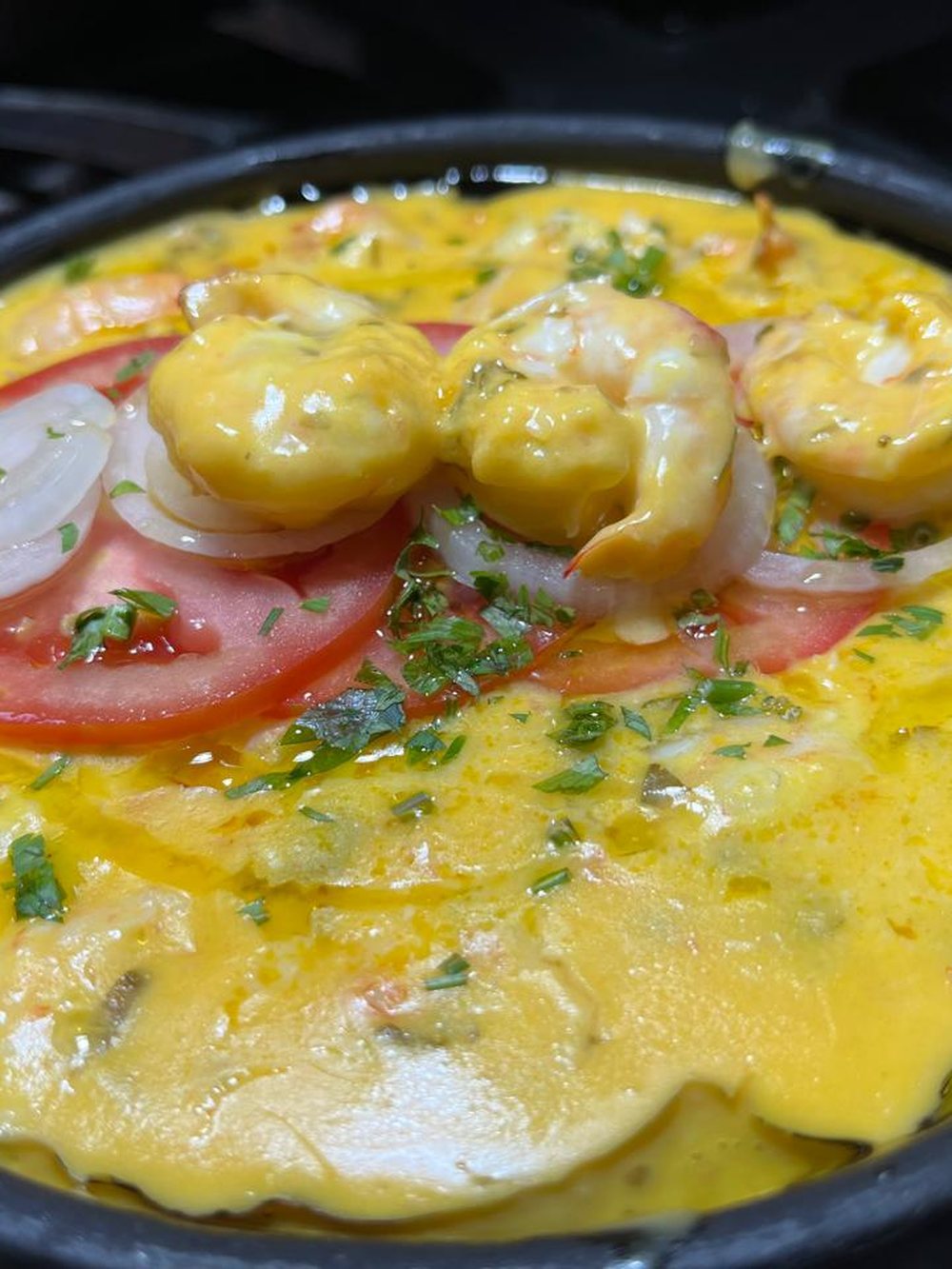 Bobó de camarão served in the clay pot, with shrimp, tomato and onion on top.