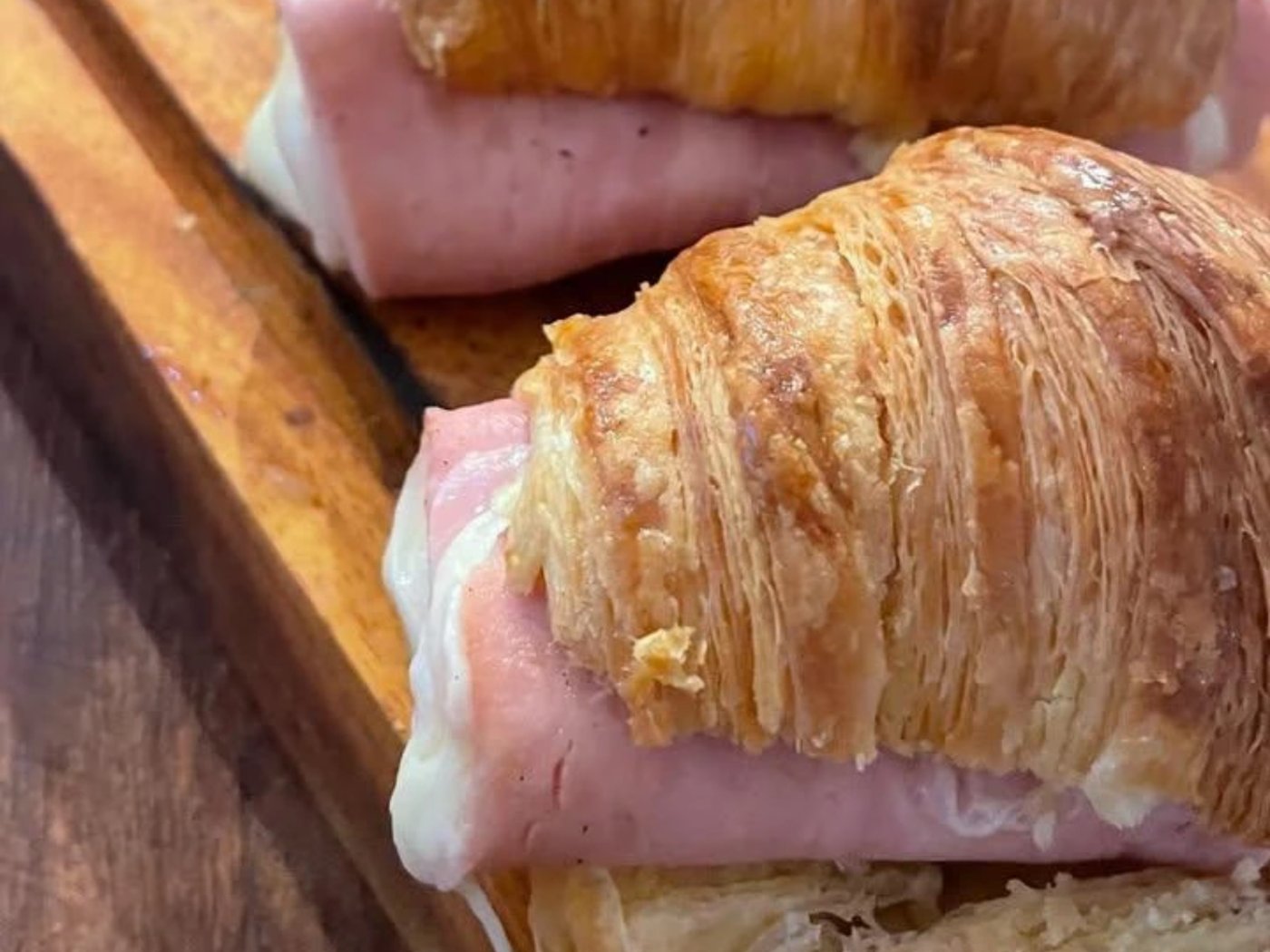 Medialunas filled with ham and cheese, on a wooden board.
